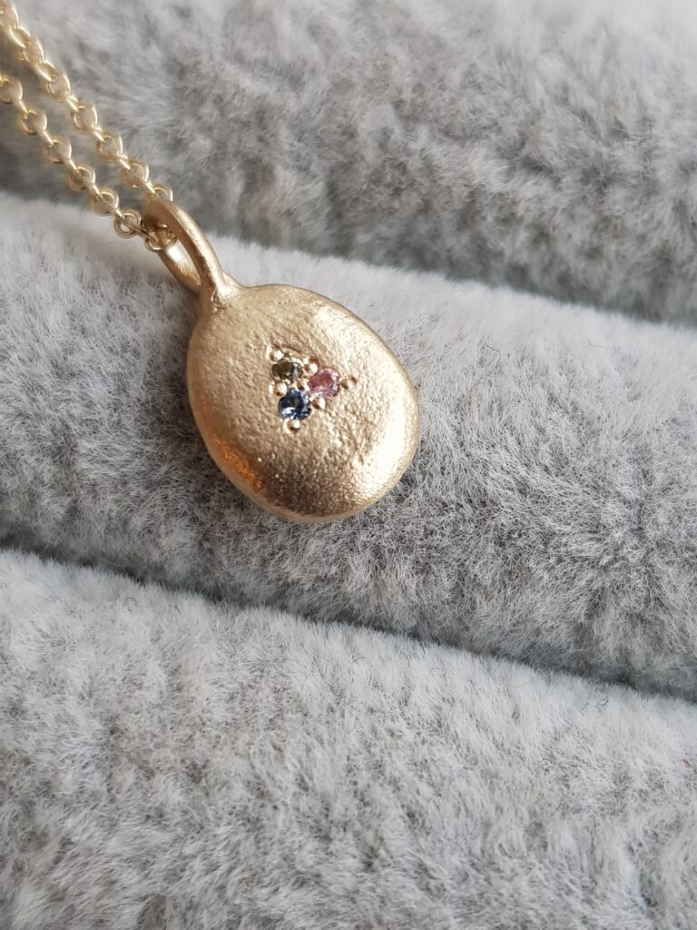 Close up of 9ct yellow gold with pastel sapphire pendant